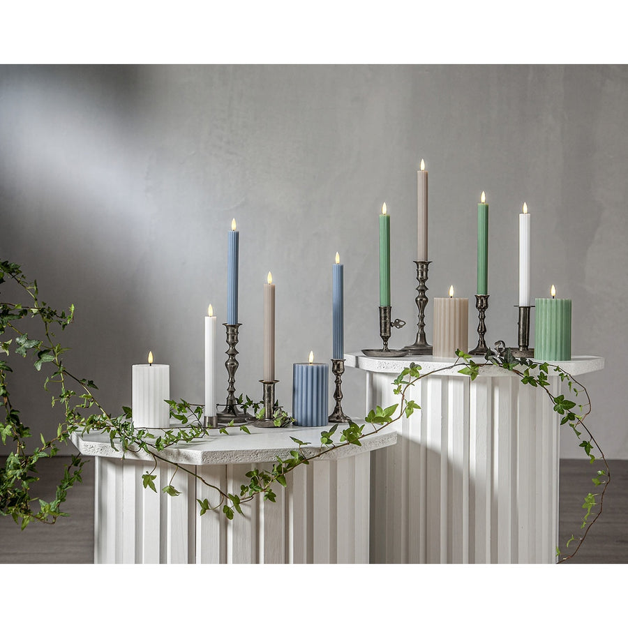 Stripe LED gyertya kollekció különböző méretű és színű valódi viaszból készült kannelúrás gyertyákkal, vintage gyertyatartókban elhelyezve, meleg fényű LED lánggal.
