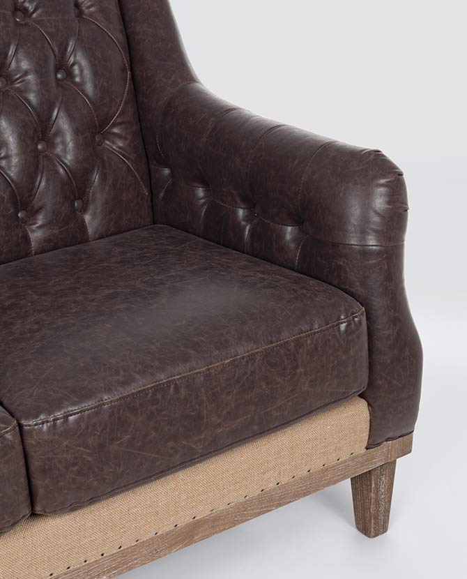 Loft stílusú, sötétbarna bőrrel kárpitozott kőrisfa kanapé karfa részlete.