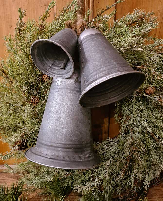Rusztikus vidéki stílusú, óriás méretű, 14-21-29 cm magas, antikolt felületű, 3 darabos karácsonyi kézműves bádogharang szett fenyőkoszorún 