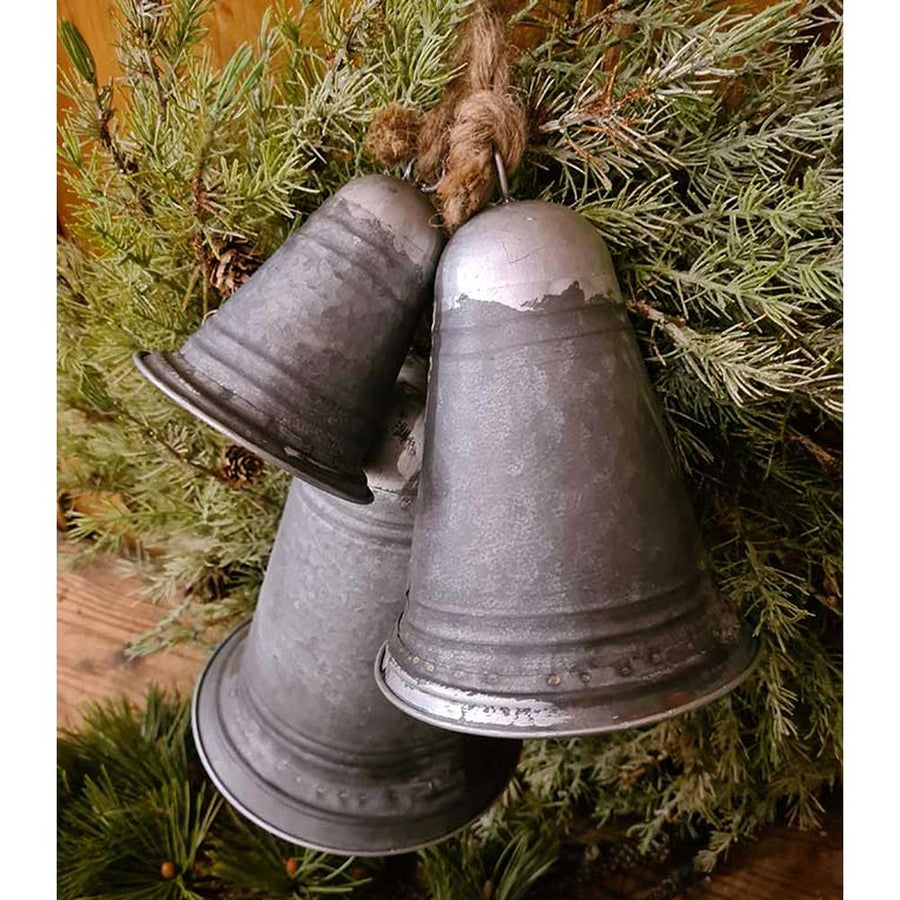 Rusztikus vidéki stílusú, óriás méretű, 14-21-29 cm magas, antikolt felületű, 3 darabos karácsonyi kézműves bádogharang szett fenyőkoszorún