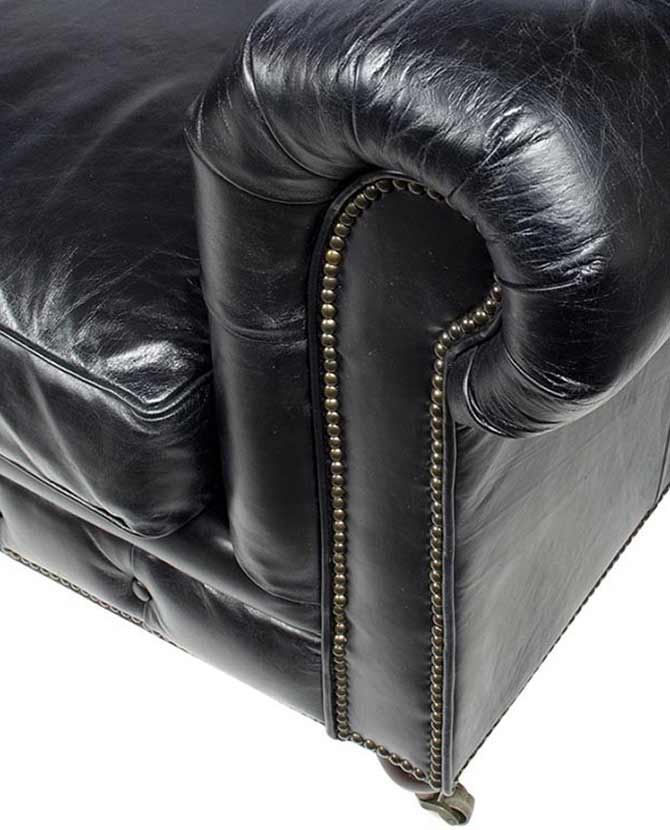 Klasszikus stílusú, antikolt fekete színű, bőr Chesterfield kanapé karfa részlete.