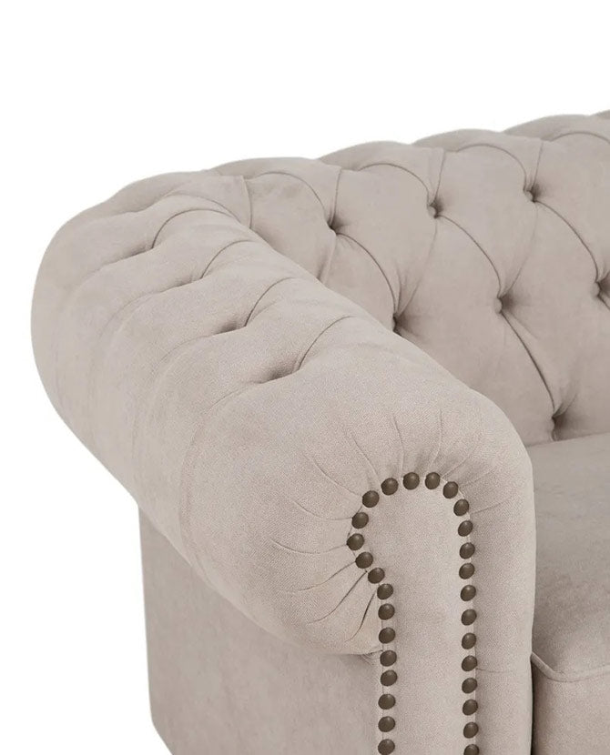 Bézs színű Chesterfield kanapé karfája, bronz szegecsekkel díszítve.