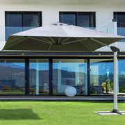 Modern stílusú épület füves udvarán álló fémvázas napernyő..