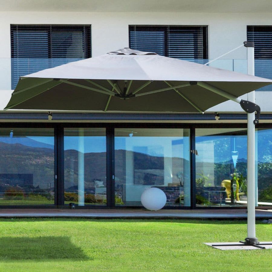 Modern stílusú épület füves udvarán álló fémvázas napernyő..
