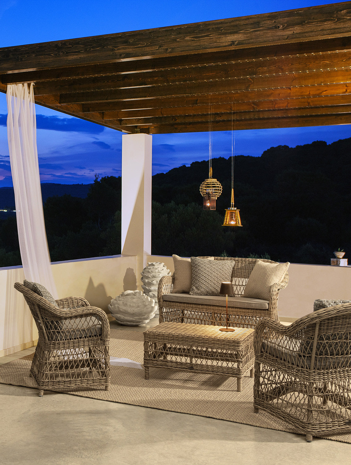 Mediterrán teraszon álló vintage stílusú, négyrészes, natúr színű műrattan kerti ülőgarnitúra.