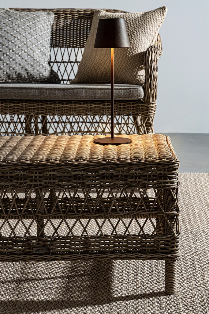 Mediterrán teraszon álló vintage stílusú, négyrészes, natúr színű műrattan kerti ülőgarnitúra.