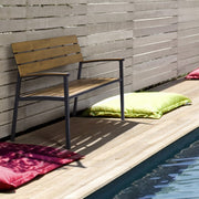 Medence szélén álló fémvázas kerti pad.