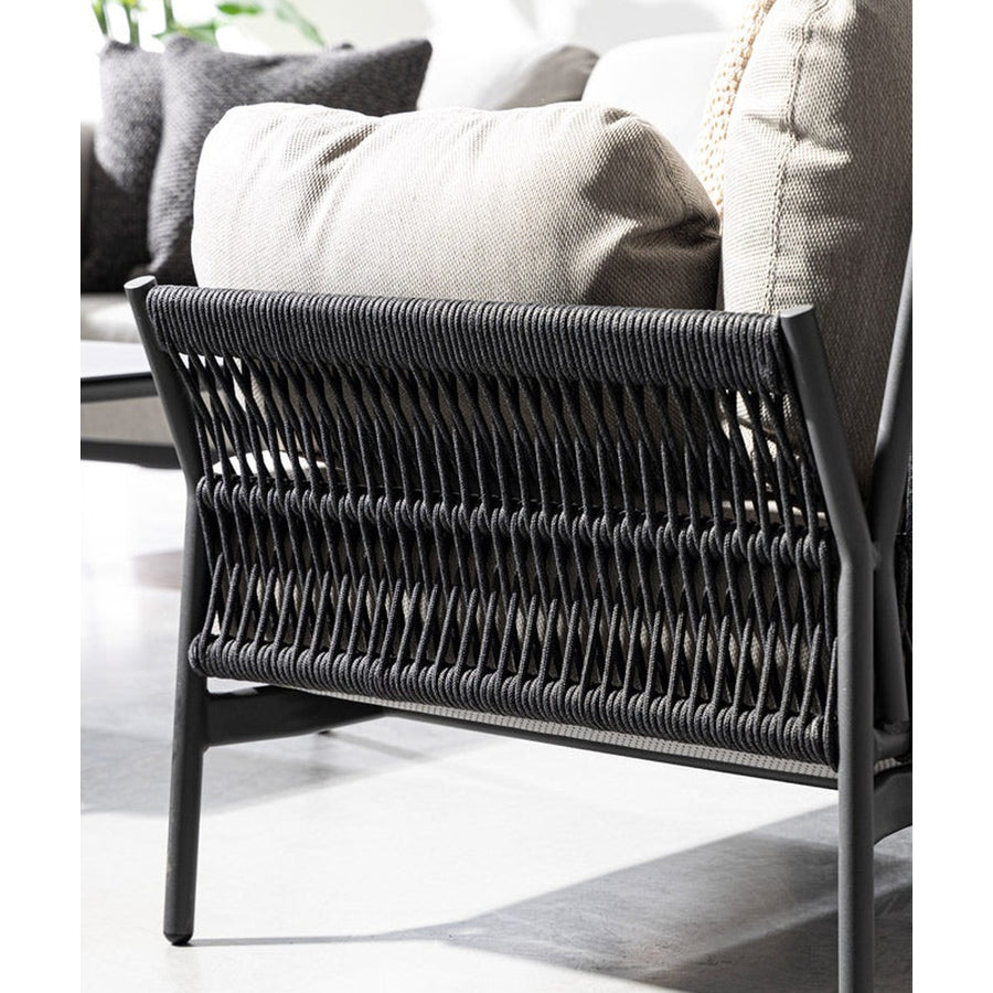 Napsütötte teraszon álló, kortárs stílusú, fekete és világosszürke kültéri fotel részlete.