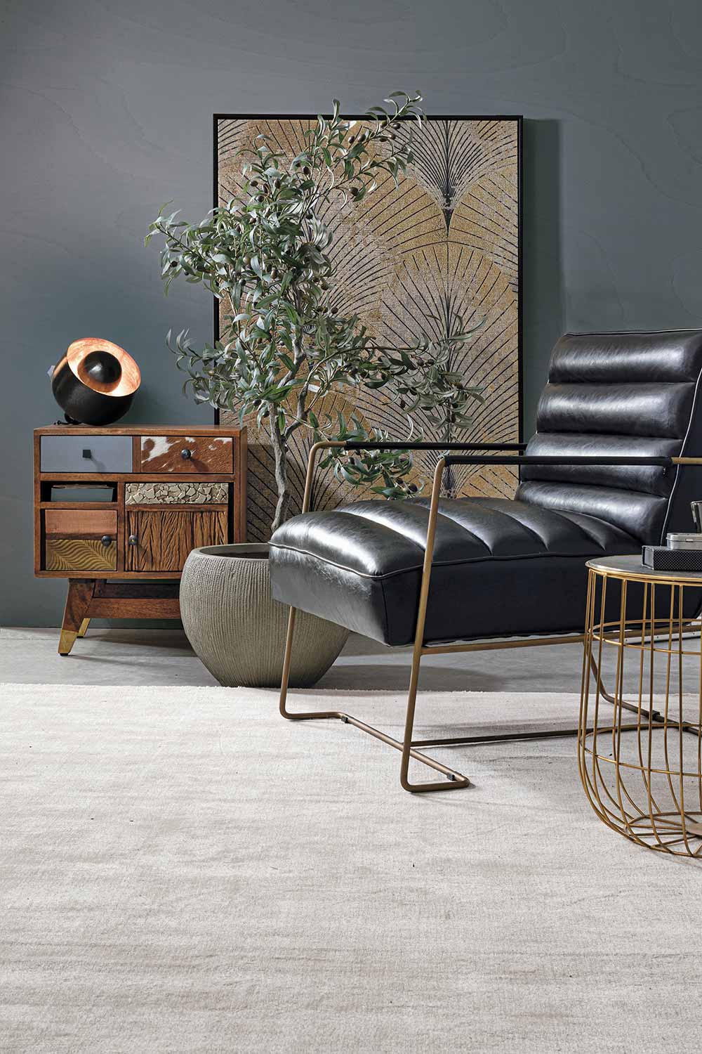 Loft stílusú nappaliban álló fekete műbőr fotel, kis momóddal és cserepes növénnyel.