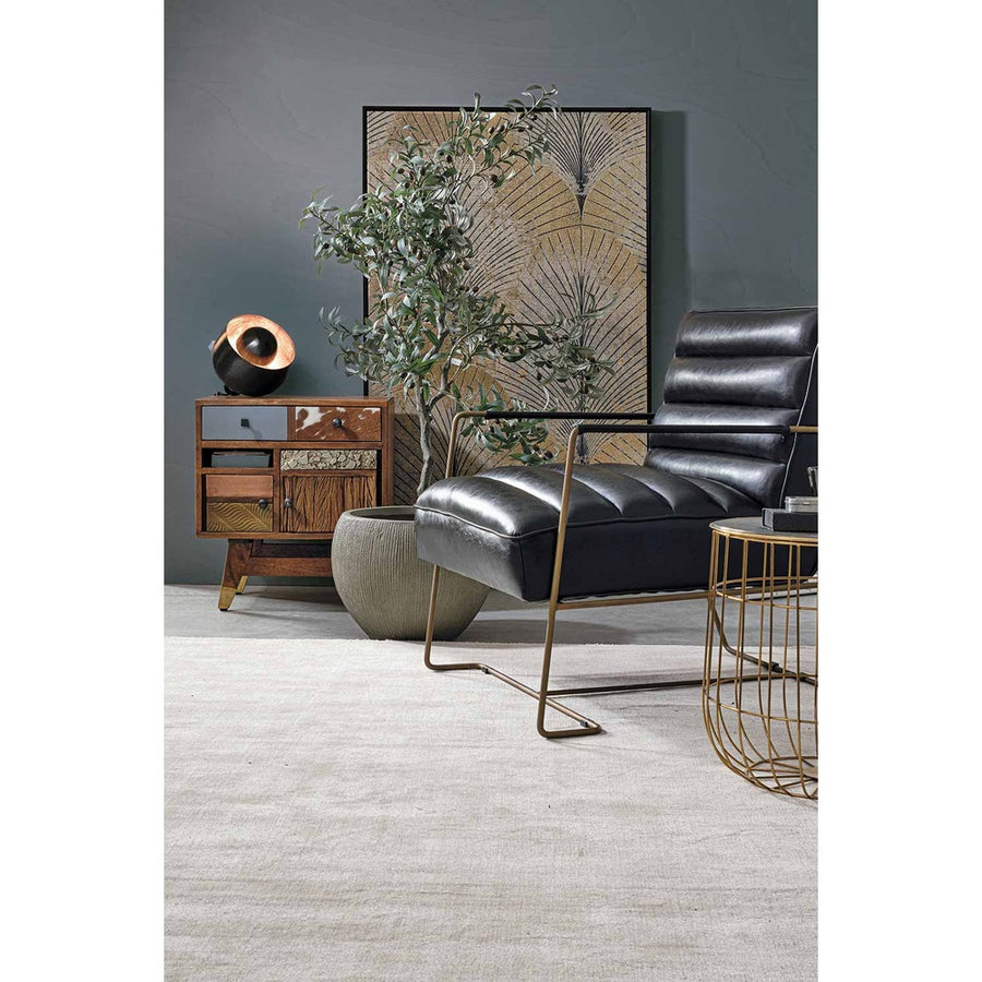 Loft stílusú nappaliban álló fekete műbőr fotel, kis momóddal és cserepes növénnyel.