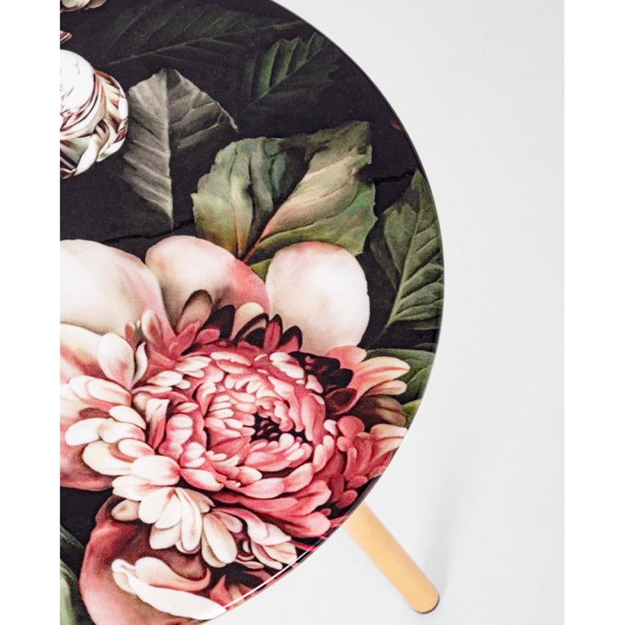 Acélból készült kisasztal arany színű lábakkal és virágmintás zománcfestéssel a fedlapján.