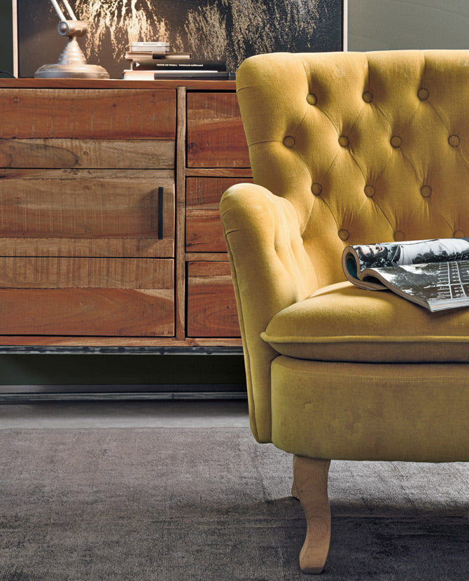 Lost stílusú nappaliban, komód előtt álló mustársárga színű vintage stílusú fotel.