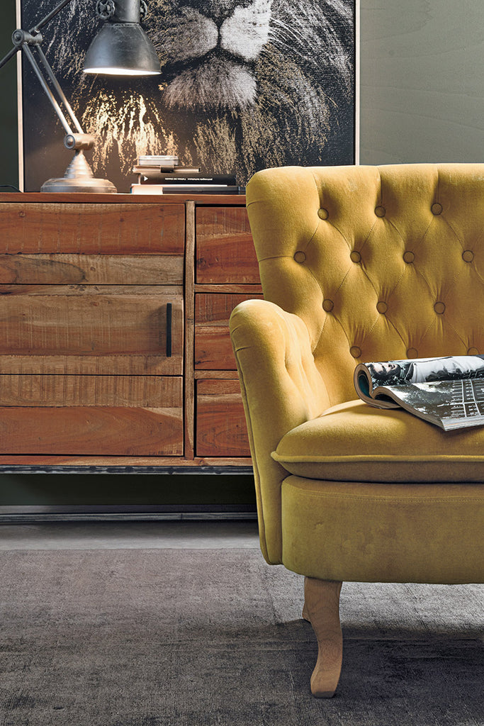 Lost stílusú nappaliban, komód előtt álló mustársárga színű vintage stílusú fotel.