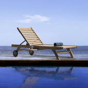 Medence szélén álló kortárs teakfa napozóágy.