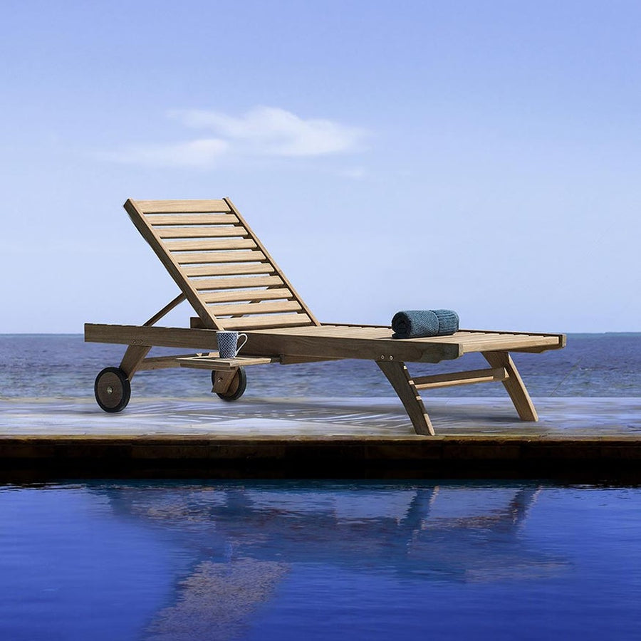 Medence szélén álló kortárs teakfa napozóágy.