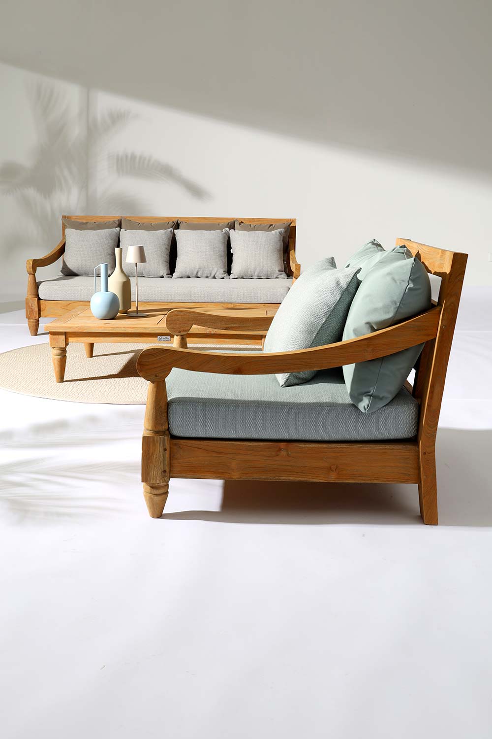 Keleti stílusú teakfa fotel bézs színű ülő- és hátpárnákkal fedett teraszon.
