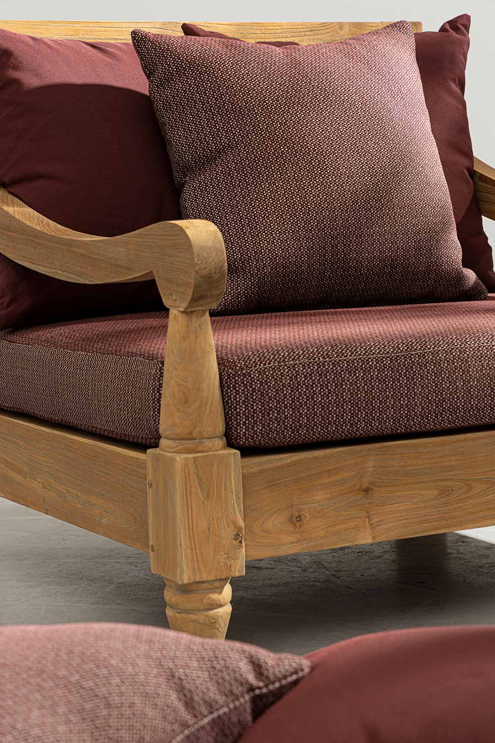 Keleti stílusú teakfa fotel hátoldala bordó színű ülő- és hátpárnákkal.