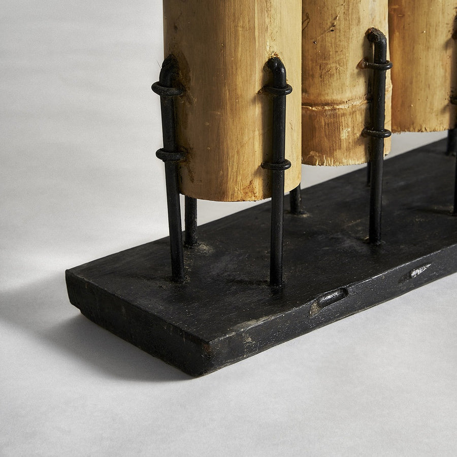 A trópusi stílusú, natúr színű térelválasztó fekete színű, fém talapzatának részlete..