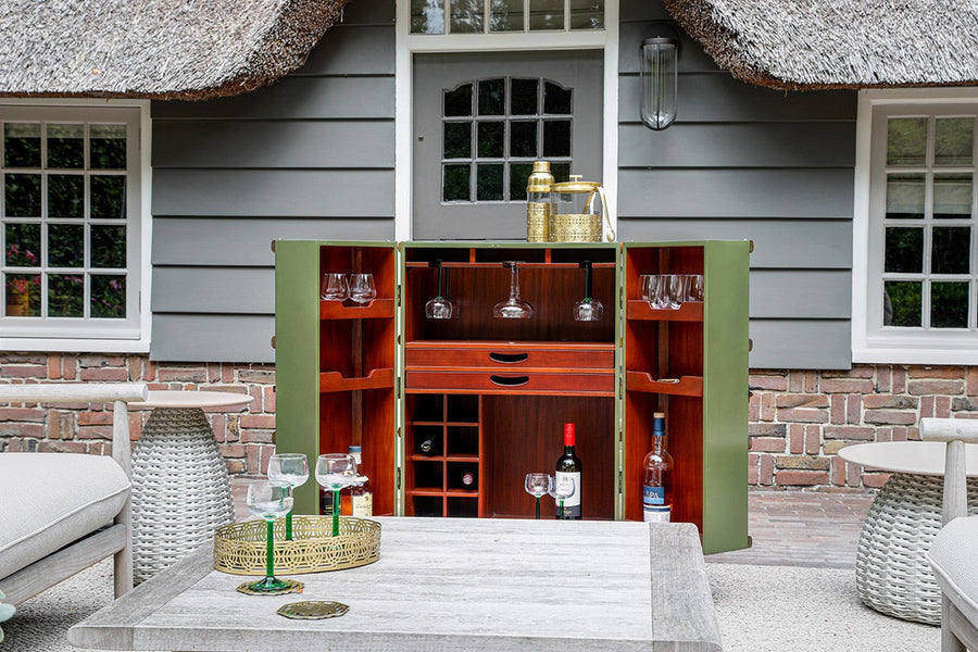 Nádtetős ház teraszán, kertibútorok mellett álló utazóláda bárszekrény.