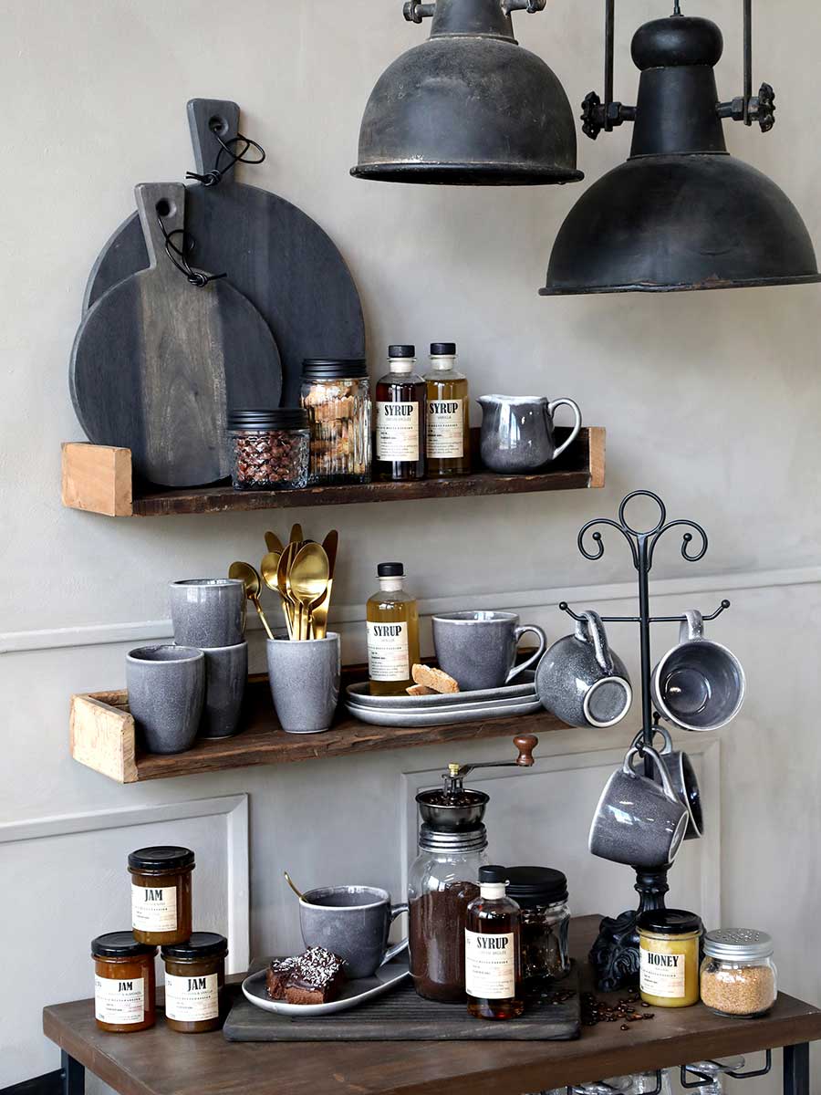 Loft stílusú kávézó, kis pulttal, polcokkal és két darab fekete színű, fém ipari stílusú lámpával.