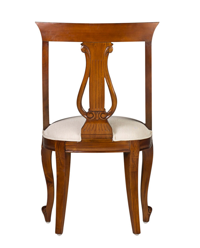 Klasszicista stílusú mahagóni karosszék, bézs ülőfelülettel. A bútor háttámláján gyönyörűen faragott lant található.
