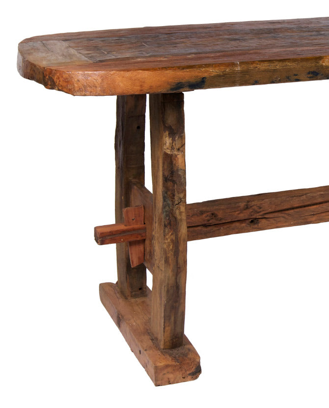 Country stílusú, újrahasznosított teakfából készült étkezőasztal. A rusztikus megmunkálású asztallap négy enyhén ívelt, masszív lábon áll, melyeket egy keresztfa fog össze hosszában..