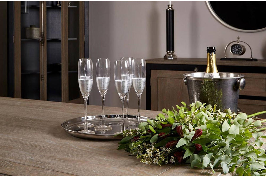 Ezüstszínű fémmel díszített pezsgőspoharak, fém tálcán , fa asztalon. 