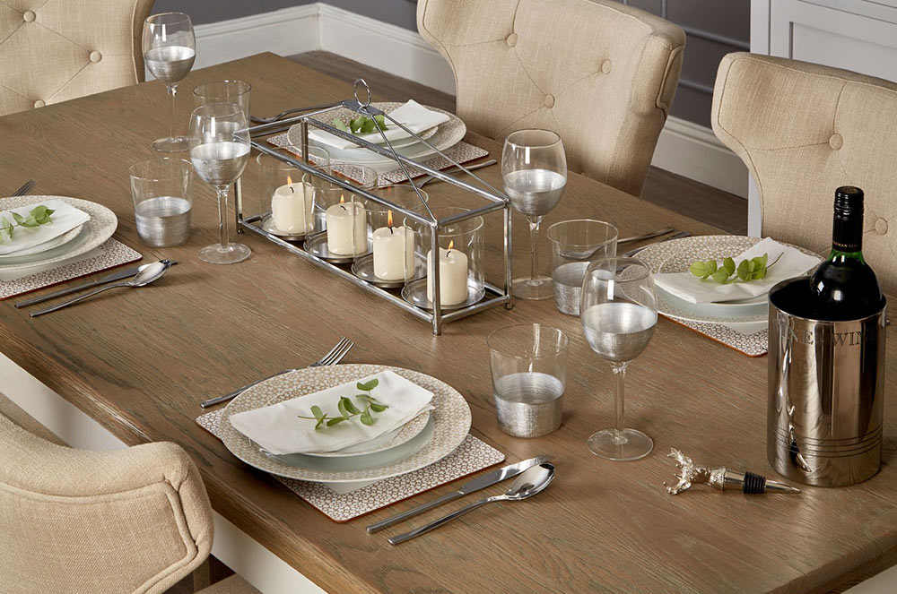 Modern, ezüstszínű fémmel díszített, röviditalos és boros üveg poharak, terített ünnepi asztalon.