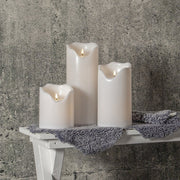 Élethű, meleg fehér fényű, fehér színű LED gyertyák kültéri padon.