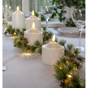 LED-es vörösfenyő girlanddal díszített karácsonyi asztal LED gyertyákkal.