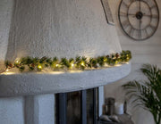 LED-es vörösfenyő girlanddal díszített karácsonyi kandalló.