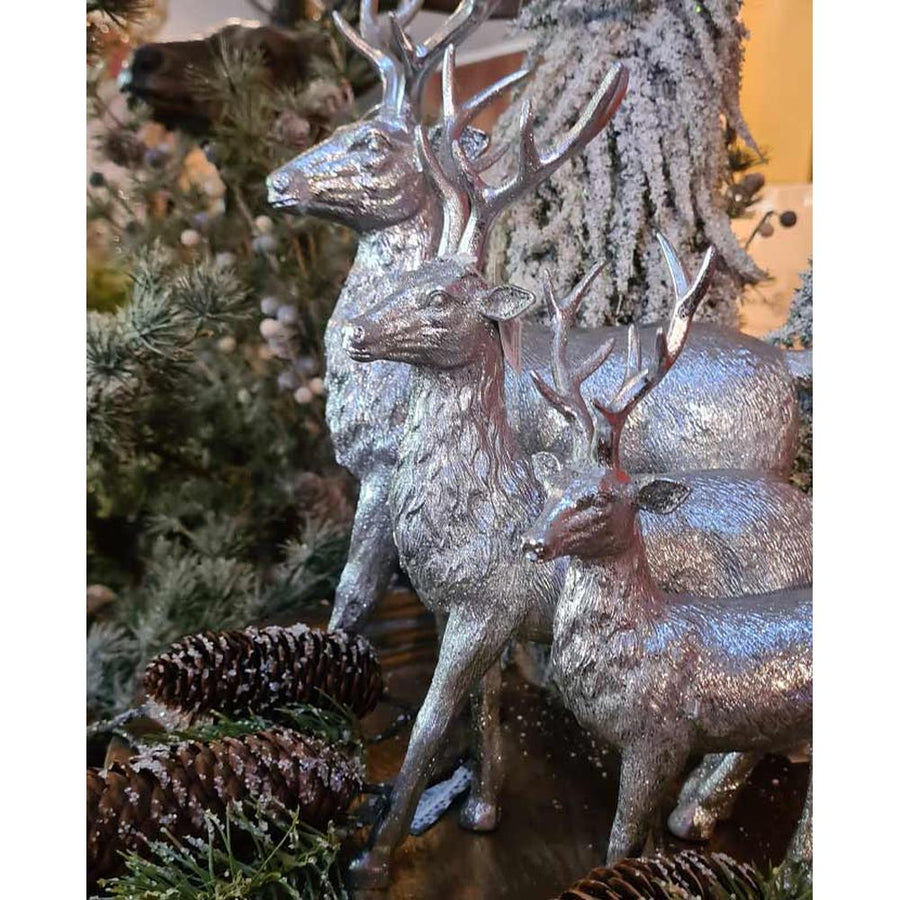 Glamour stílusú, 28 cm magas, ezüst színű karácsonyi szarvas figura többféle méretben tobozok és fenyők között