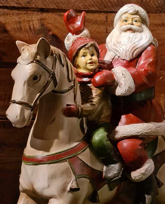 Vintage stílusú, karácsonyi hintaló Télapóval és kisfiúval barna színű deszkafal előtt