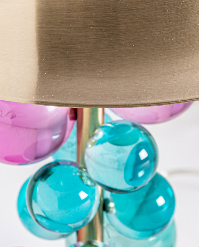 Bohó stílusú, arany színű fém asztali lámpa márvány lapon, türkiz és rózsaszín üveggömbökkel díszítve.