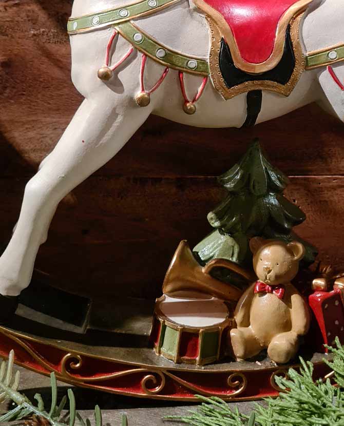 Vintage stílusú, 29,5 cm hosszú, fehér és piros színű karácsonyi hintaló ajándékokkal barna deszkafal előtt 