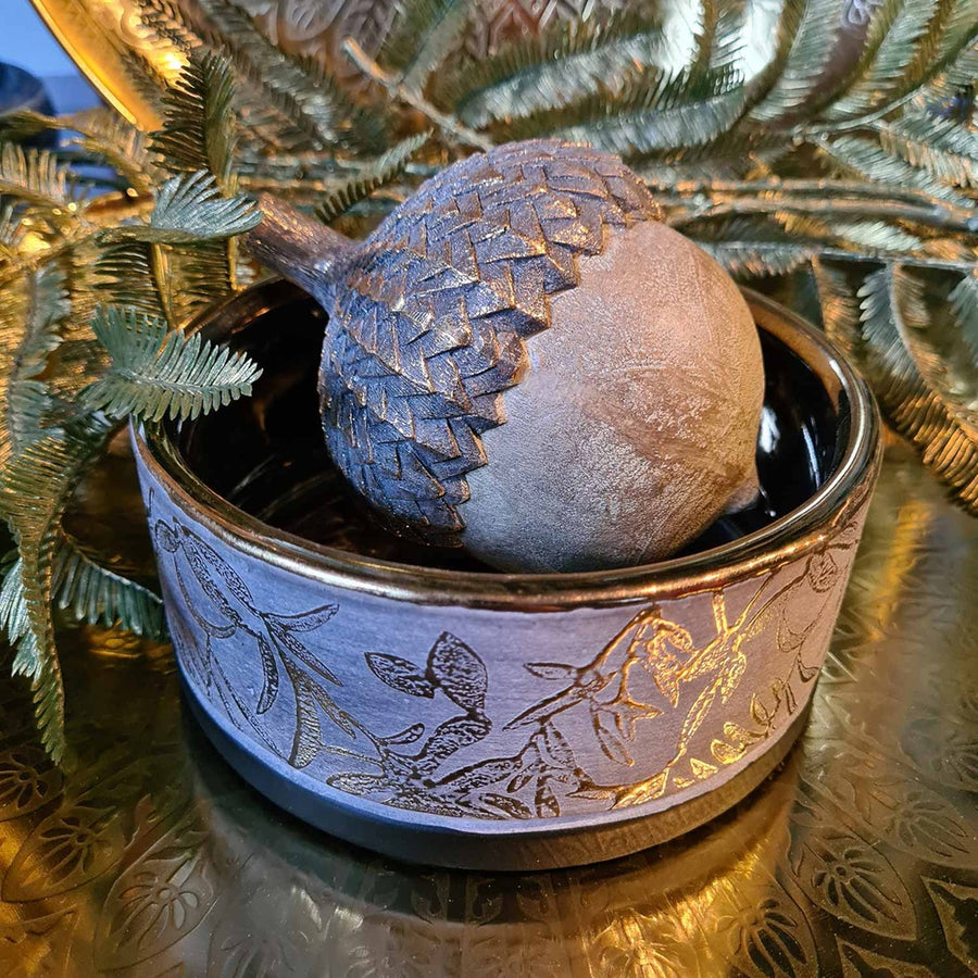 Aranyszínű dombormintával díszített, modern, glamour stílusú kerámia arany tál, aranyszínű makkokkal, fém tálcán.