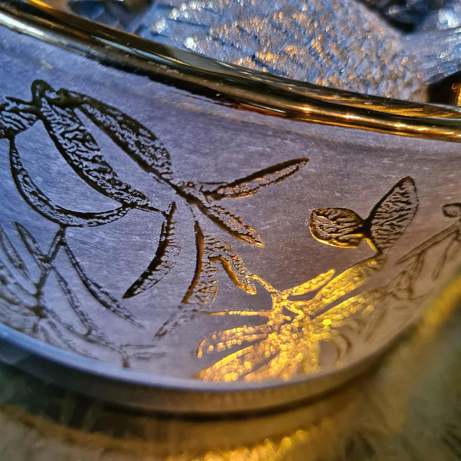 Aranyszínű kerámia tál oldalán látható arany minta.