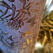 Aranyszínű dombormintás váza oldala.