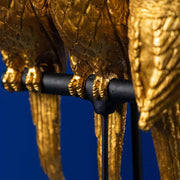 Aranyszínű papagáj figurákkal díszített, 79 cm magas, trópusi, glamour stílusú asztali lámpa, kék háttér előtt.