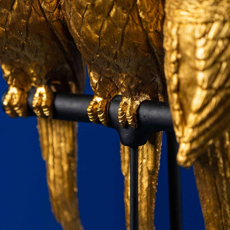 Aranyszínű papagáj figurákkal díszített, 79 cm magas, trópusi, glamour stílusú asztali lámpa, kék háttér előtt.