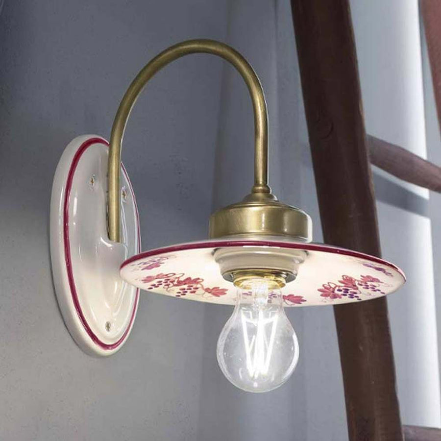 Festett motívumokkal díszített, mázas kerámiából és fémből készült kézműves falilámpa.