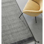 Szürke gyapjú szőnyeg, sárga fotellel.