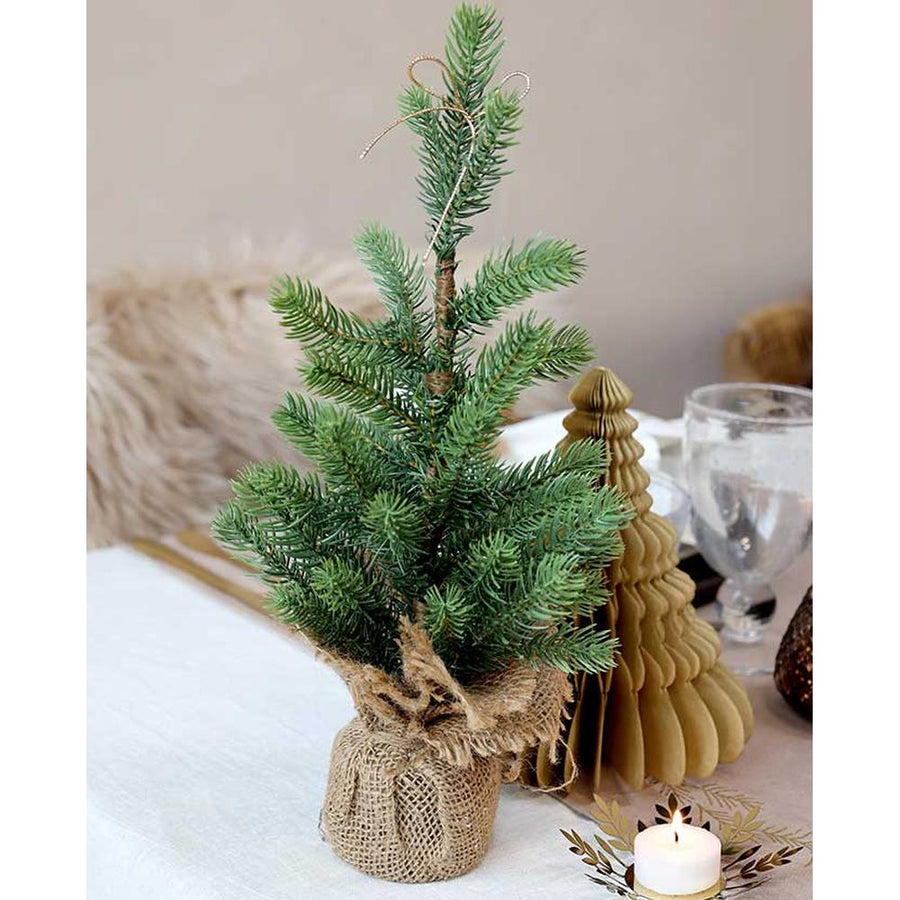 Karácsonyi asztalt díszítiő, élethű, kisméretű deko fenyőfa jutazsákban.