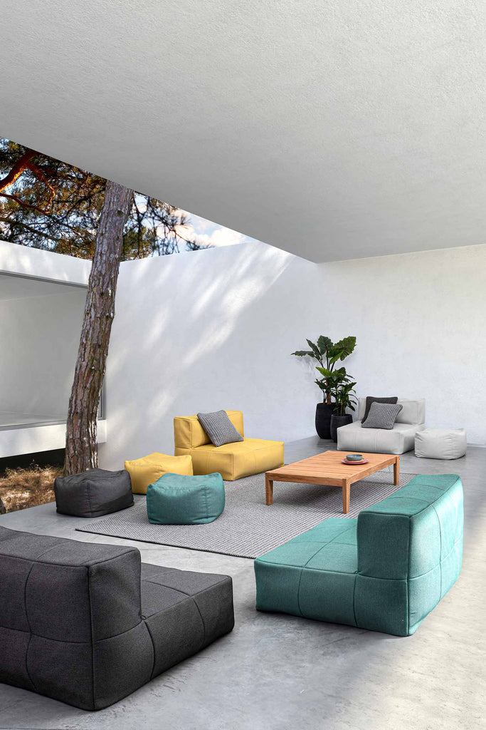 Modern, kortás formavilágú kerti fotelek és puffok egy átrium udvarában.