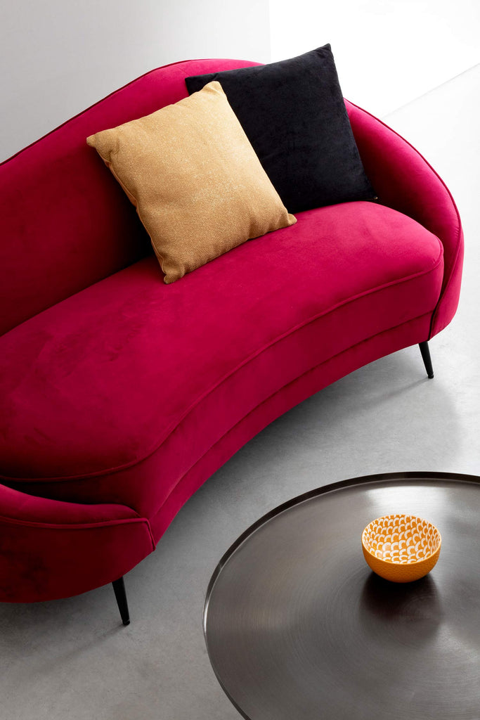 Modern, kortárs stílusú, fekete színű, nikkelezett acélból készült, kör alakú dohányzóasztal, bordó íves kanapéval.