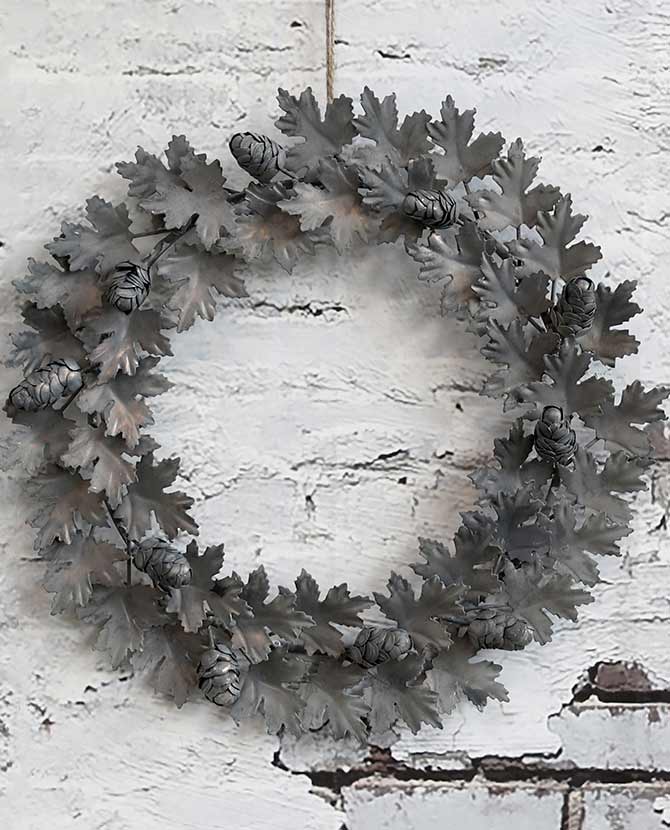 Vidéki stílusú, antikolt felületű, fém tölgyfalevelekből készült, fém tobozokkal díszített karácsonyi koszorú.