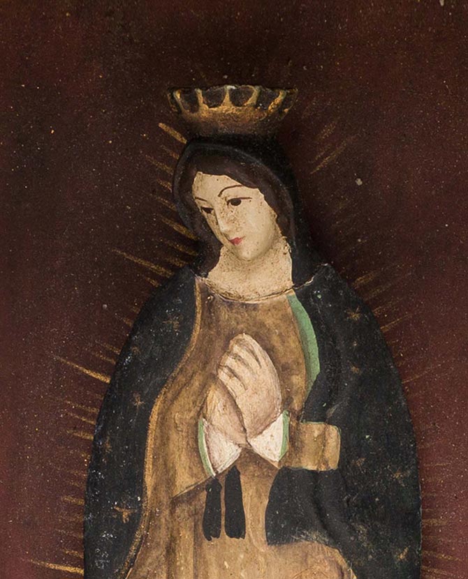 Szoborfülkés fém képkeretbe foglalt, a Guadalupei Szűzanyát ábrázoló figura.