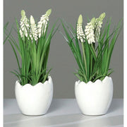 Krém színárnyalatú mű gyöngyike virág, tojás formájú, fehér színű kerámia kaspóban.