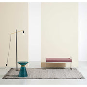 Barna szőnyeg, modern paddal, kék dohányzóasztallal és modern állólámpával.