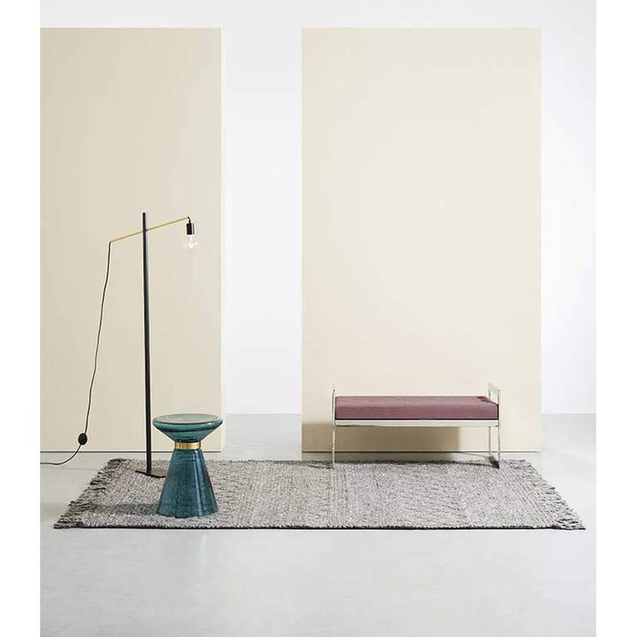 Barna szőnyeg, modern paddal, kék dohányzóasztallal és modern állólámpával.